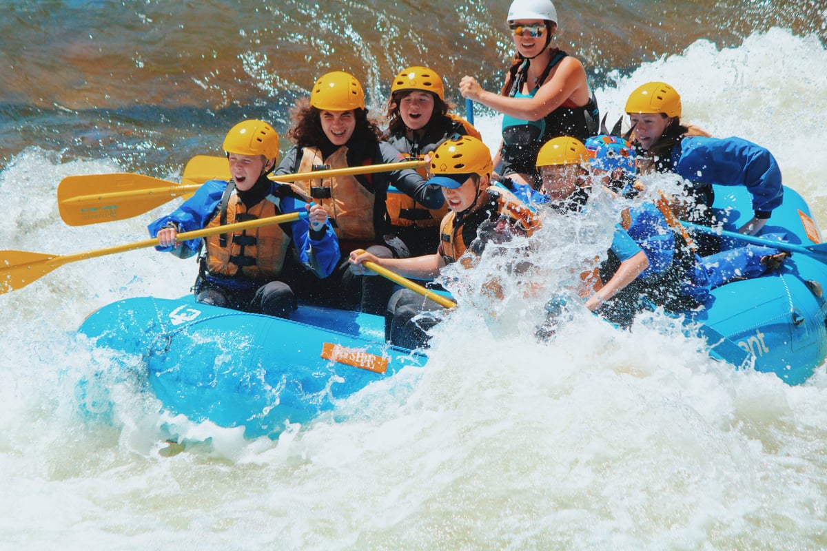 Raft guide and campers crash through a rapid on an Expedition Program